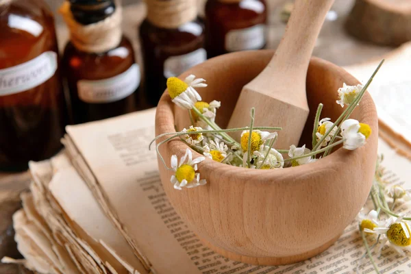 Oud boek met droge bloemen in mortel en flessen op tafel close-up — Stockfoto