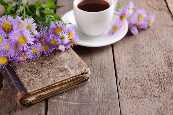 Libro viejo con hermosas flores y taza de té en la mesa de madera de cerca — Foto de Stock