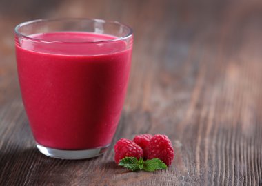 Ahşap arka plan üzerinde çilek ile Ahududu milkshake bardak