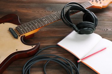 Elektro gitar ahşap masa üstünde defter ve kulaklık ile yakın çekim
