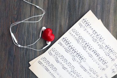 Ahşap arka plan üzerinde kırmızı kalp ve müzik notlar ile kulaklık
