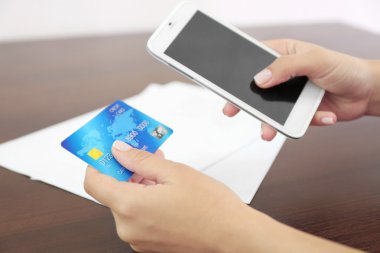 Kadın ahşap masa arka plan üzerinde mobil bankacılık uygulaması ile smartphone cep telefonu ile hesap bakiyesi doğrular
