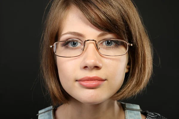 Aantrekkelijke jonge vrouw met een bril op grijze achtergrond — Stockfoto