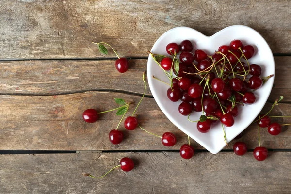 Cherries on plate, on wooden background — Stock Photo, Image