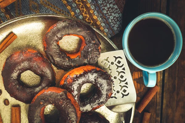 Delicious doughnuts with chocolate icing and cup of coffee on table close up — Stock Photo, Image
