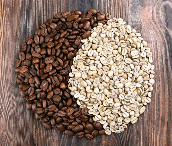 Green and brown coffee beans on wooden table close up — Stock Photo, Image