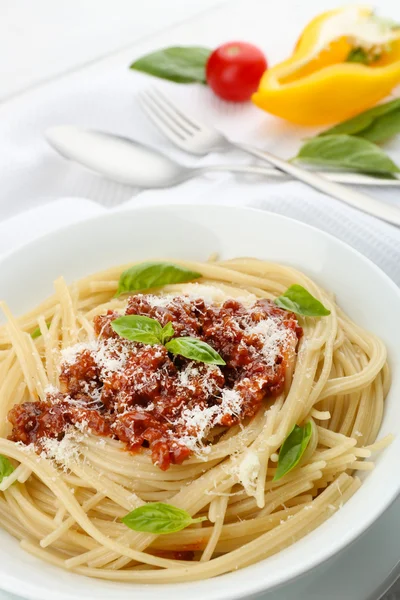 Спагетті Болонья з пармезановим сиром у білій мисці, на кольоровому дерев'яному фоні — стокове фото
