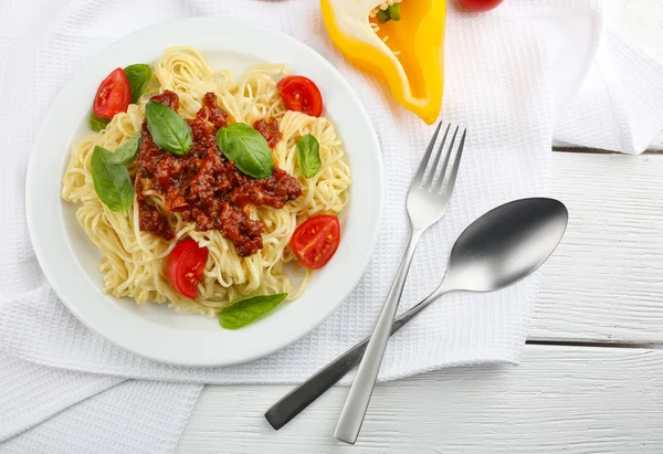 Spaghete Bolognese pe placă albă, pe fundal de lemn color — Fotografie, imagine de stoc
