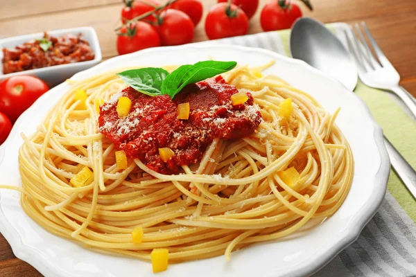 Spaghetti mit Tomatensauce, Paprika und Käse auf weißem Teller, auf farbigem Holzhintergrund — Stockfoto