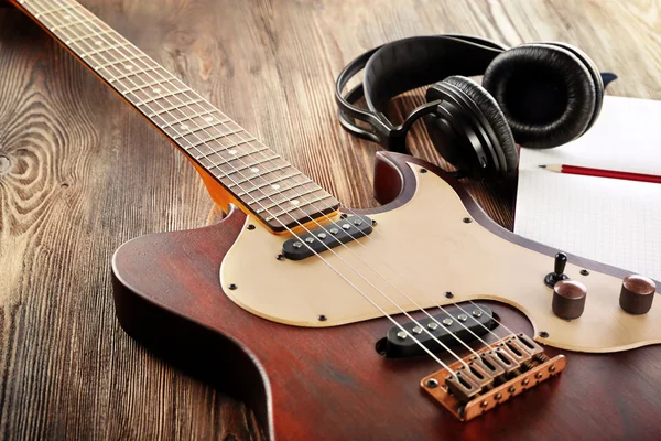 Elektro gitar ahşap masa üstünde defter ve kulaklık ile yakın çekim — Stok fotoğraf