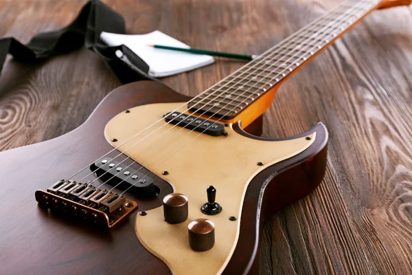 Electric guitar with notebook on wooden table close up — Stock Photo, Image