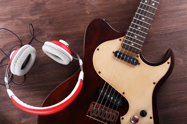 Electric guitar with headphones on wooden table close up — Stock Photo, Image