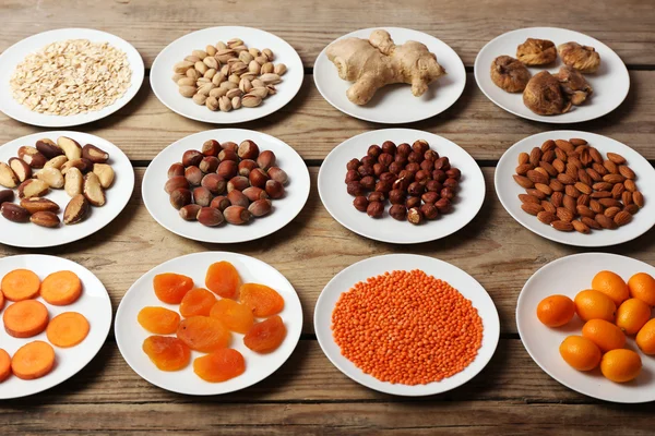 Различные продукты на блюдцах на деревянном столе крупным планом — стоковое фото