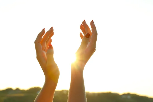 Las manos femeninas sobre el fondo del cielo soleado — Foto de Stock