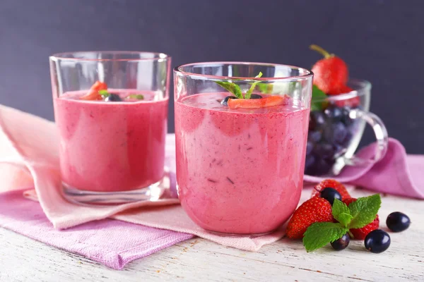 Óculos de smoothie de baga na mesa de madeira no fundo escuro — Fotografia de Stock