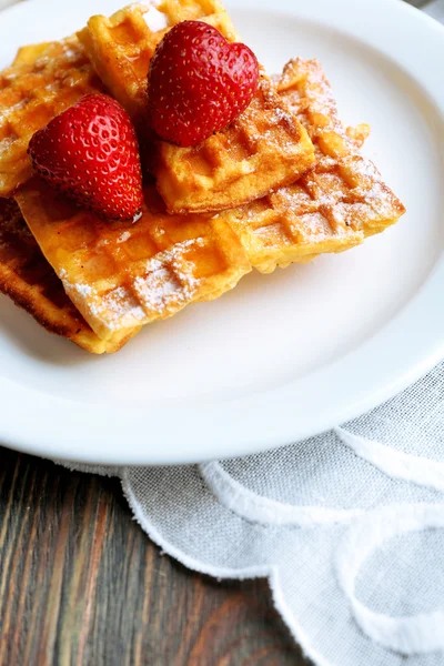 Süße hausgemachte Waffeln mit Erdbeeren auf Teller, auf Tischhintergrund — Stockfoto