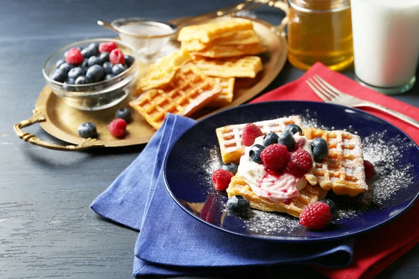 Sweet homemade waffles with forest berries and cream on plate, on dark wooden background — Stock Photo, Image
