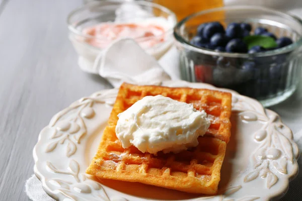 Süße hausgemachte Waffeln auf Teller, auf farbigem Holzhintergrund — Stockfoto