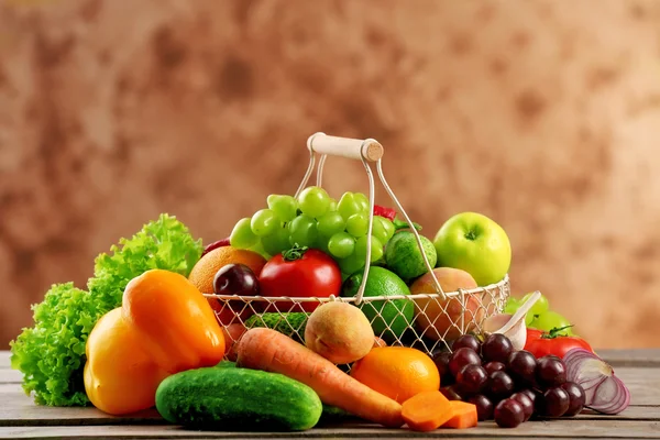 Haufen frisches Obst und Gemüse in Korb auf Holztisch in Großaufnahme — Stockfoto