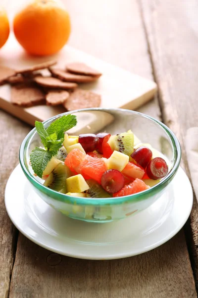 Ensalada de frutas en cuenco de vidrio, sobre fondo de madera — Foto de Stock