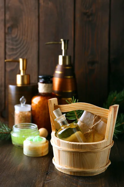 Essential oil of pine, handmade soap in wooden bucket and spa treatments on wooden background — Stock Photo, Image