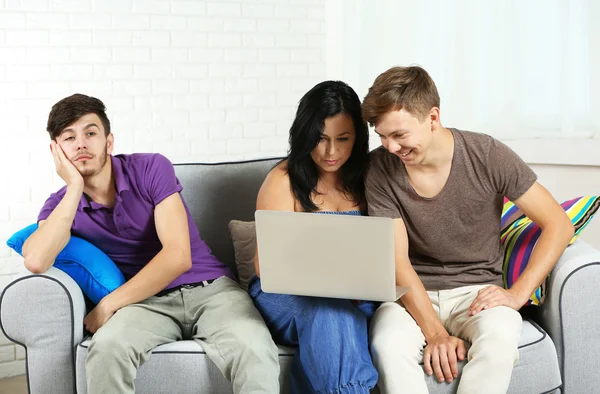 Happy family portrait with laptop sitting on sofa at home — Stock Photo, Image