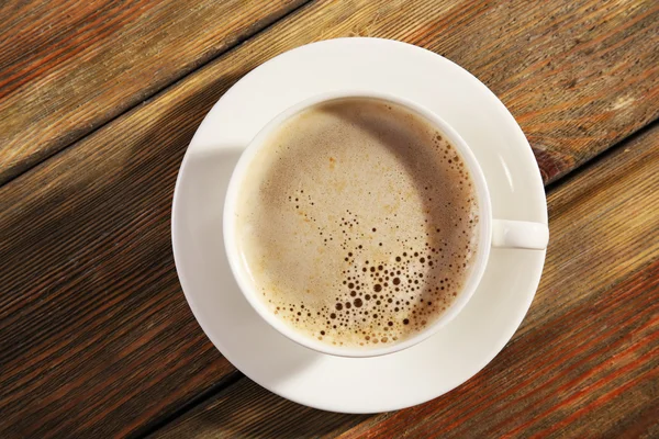 Bir fincan köpüklü kahve, ahşap masa, üst manzara. — Stok fotoğraf