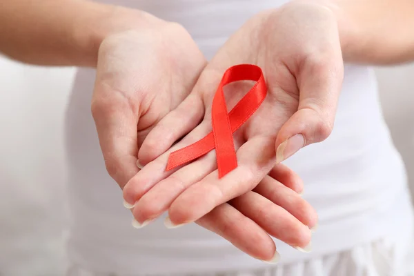 Female hands holding red ribbon sign, closeup — Stock Photo, Image