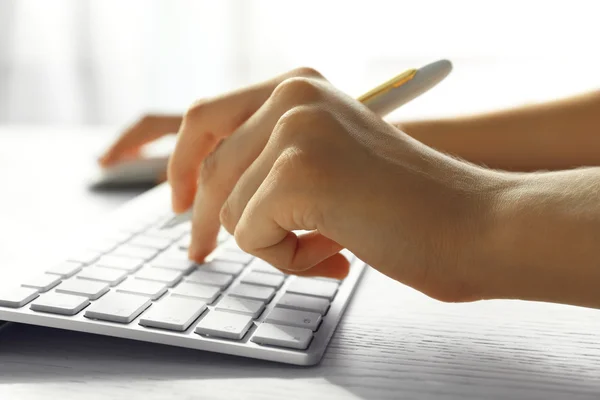 Ręka z piórem, pisanie na klawiaturze przy stole, zbliżenie — Zdjęcie stockowe