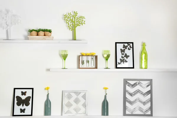 Different home objects and decoration on shelves on white wall background