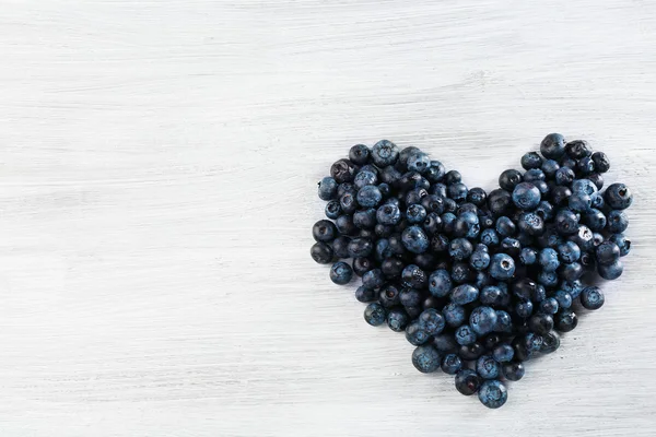 Heart of blueberries on wooden background — Stock Photo, Image