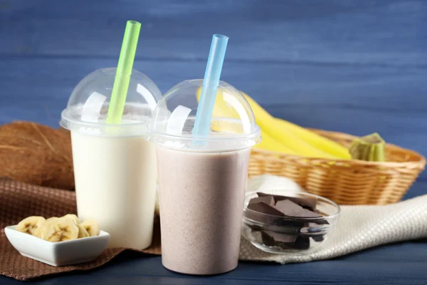 Copa de plástico de batido con plátano sobre fondo de madera de color — Foto de Stock