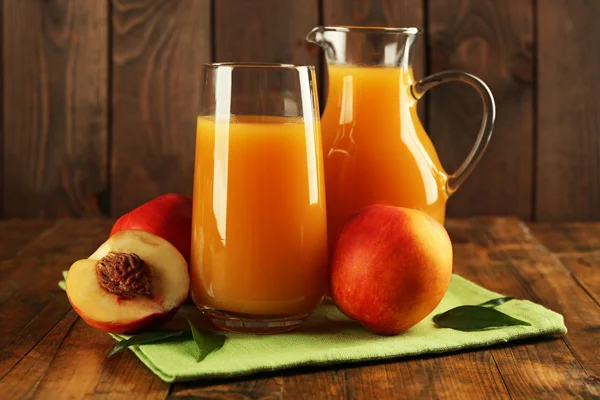 Peach juice and ripe peaches on wooden background — Stock Photo, Image