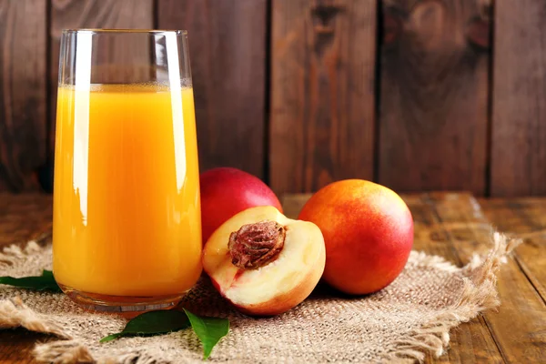 Ripe peaches and glass of juice on wooden background — Stock Photo, Image
