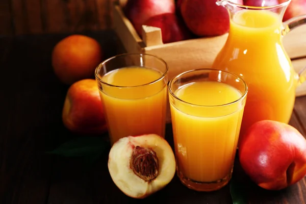 Peach juice and ripe peaches on wooden background — Stock Photo, Image