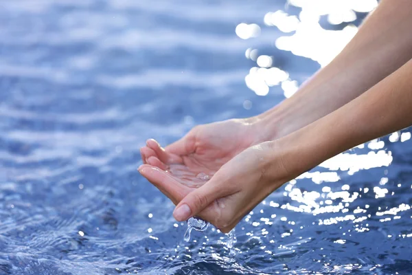Kobiece ręce dotyka wody morskiej — Zdjęcie stockowe