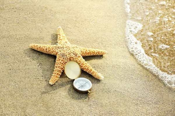 Bússola com estrela do mar no fundo da praia de areia — Fotografia de Stock