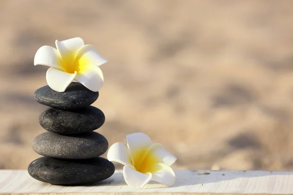 Piedras de spa con flores en la playa de arena de cerca —  Fotos de Stock