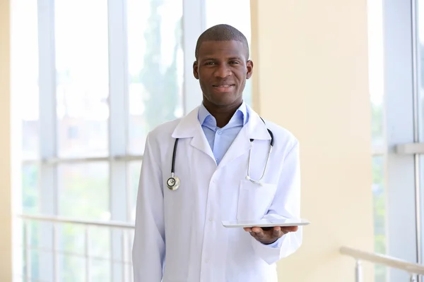 Handsome African American doctor holding digital tablet in hospital — Stock Photo, Image