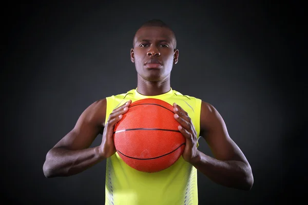 Joueur de basket afro-américain tenant le ballon sur fond sombre — Photo