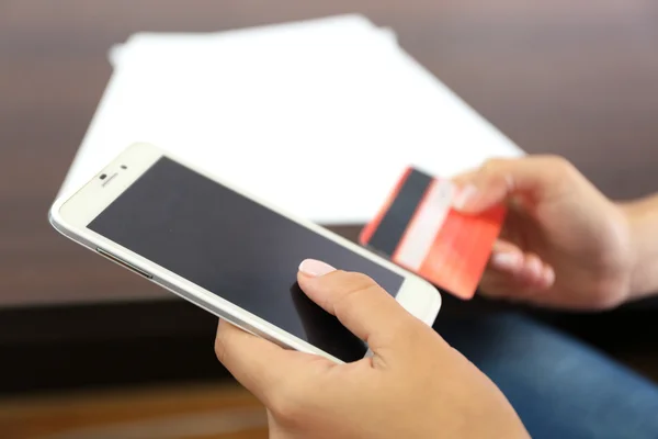 Mujer verifica saldo de cuenta en smartphone con aplicación de banca móvil sobre fondo de mesa de madera —  Fotos de Stock