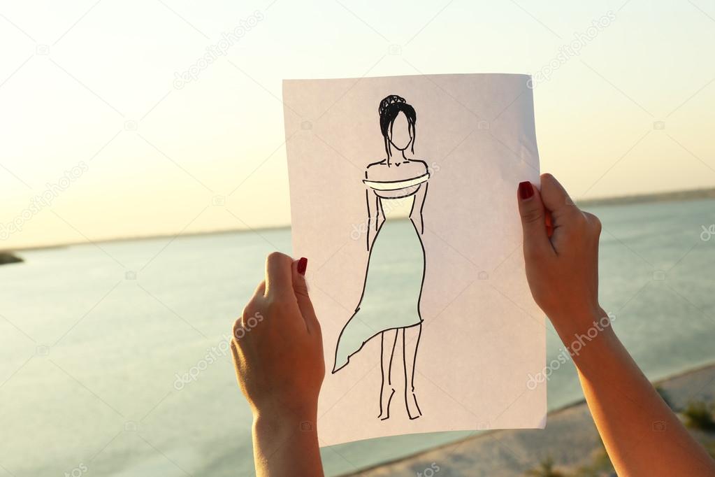 Drawing woman in cutout dress on sheet of paper on nature