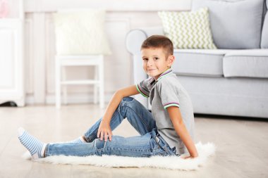 Küçük çocuk halı, eve iç arka plan üzerinde oturan