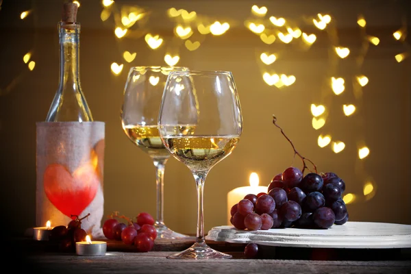 Wine glass near bottle on hearts bokeh background — Stock Photo, Image