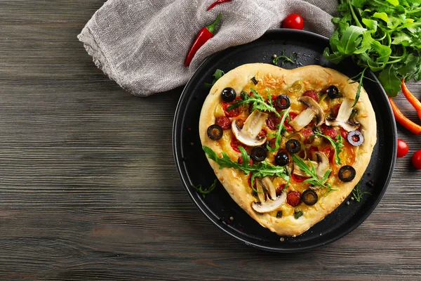 Herzförmige Pizza auf Metalltablett auf hölzernem Hintergrund — Stockfoto