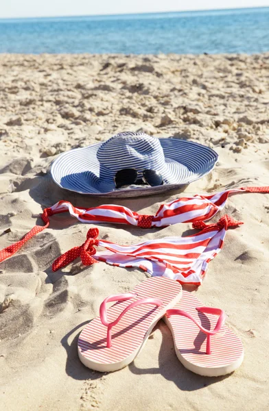 Chinelos, maiô e chapéu na praia — Fotografia de Stock