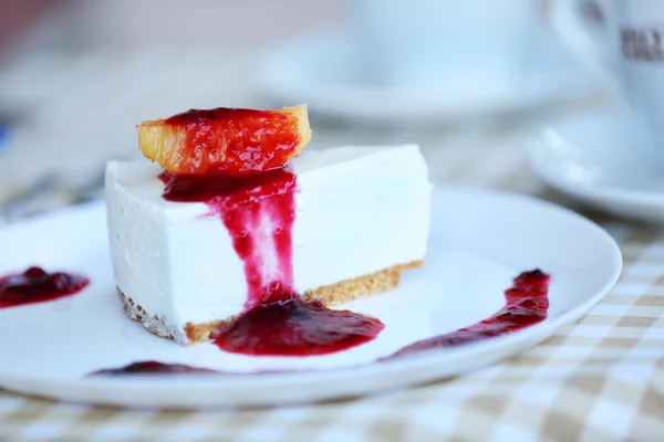 Heerlijke cheesecake met saus op tafel in café — Stockfoto