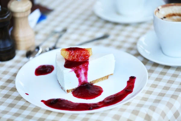 Heerlijke cheesecake met saus op tafel in café — Stockfoto