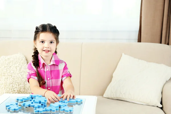 Bonito menina brincando com quebra-cabeças em casa interior fundo — Fotografia de Stock