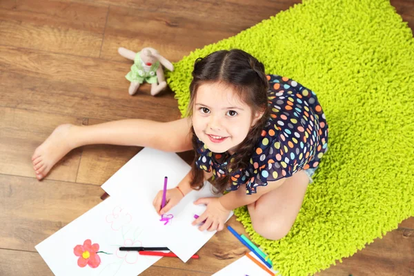 Linda niña sentada en el suelo y dibujo, en el fondo interior del hogar —  Fotos de Stock